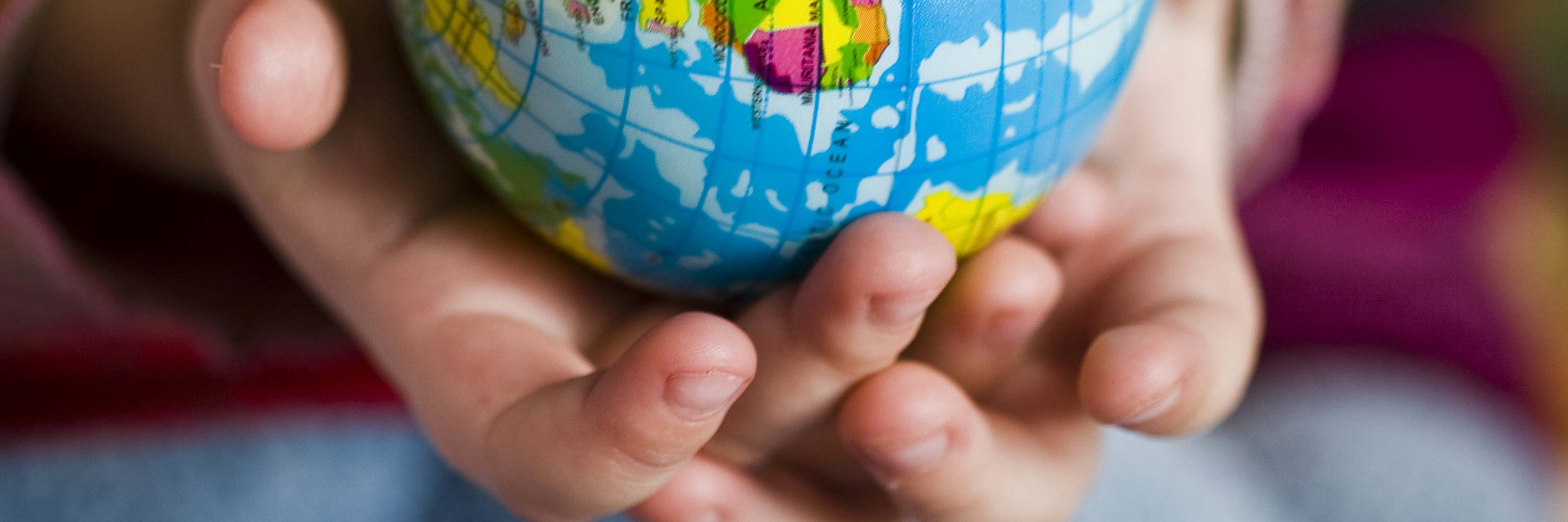 A pair of hands holding a small model of a globe